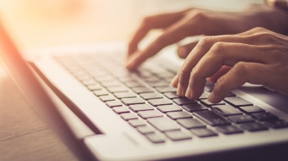 Hands typing on a laptop computer